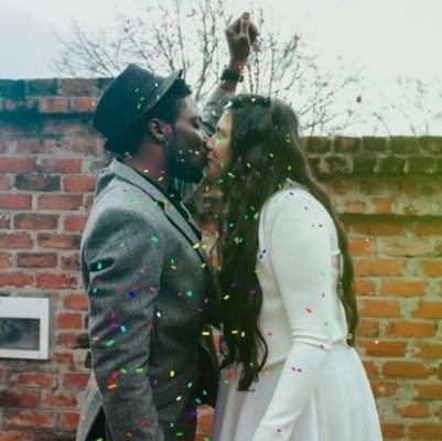 Man in hat kissing woman in white dress