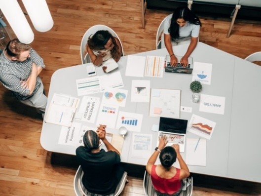 five people in the office discussing a project