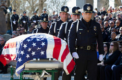 A group of police officers carry a casket at a memorial service.