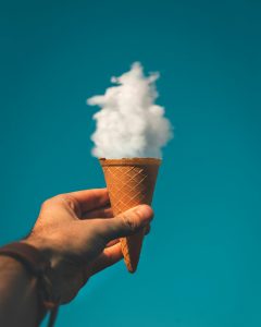 A hand holding a cone with a white cloud coming out of it.