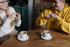 A person and person sitting at a table with cups of coffee