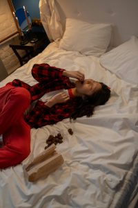 A person lying on a bed eating chocolate